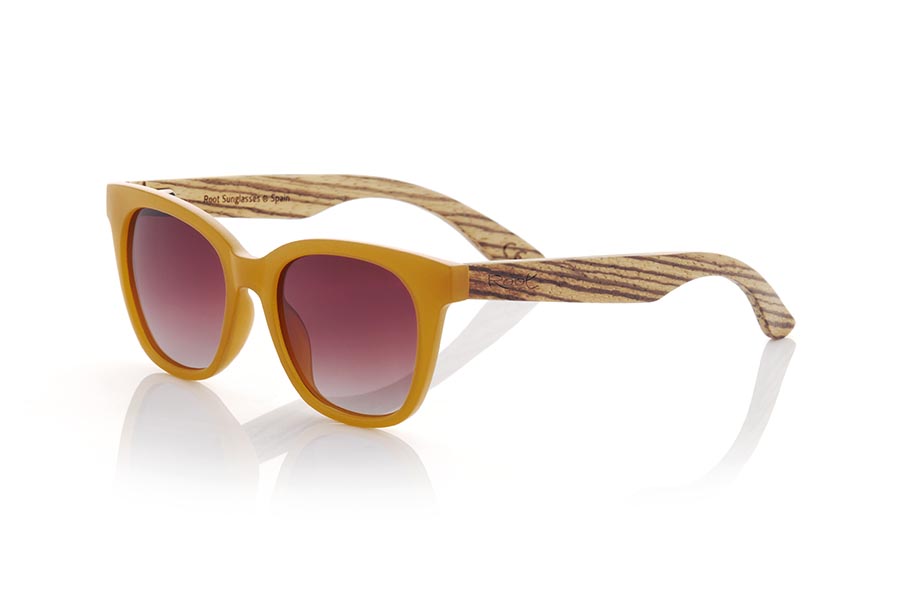 Wood eyewear of Walnut modelo NORA. NORA sunglasses combine a frame in an attractive satin orange tone with walnut wood temples to offer a fresh and natural design. This model with its rounded shapes and ideal size has a slight retro touch and is perfect for women, although it can also look good on daring men. Gradient brown or gray-toned lenses add an elegant touch to these wooden sunglasses. Enjoy a unique style and the protection you need anywhere with the NORA sunglasses from Root. Front Measurement: 143x50mm Caliber: 49 | Root Sunglasses® 